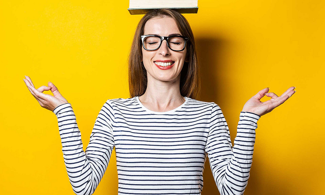 Frau hält ein Buch auf dem Kopf in Balance