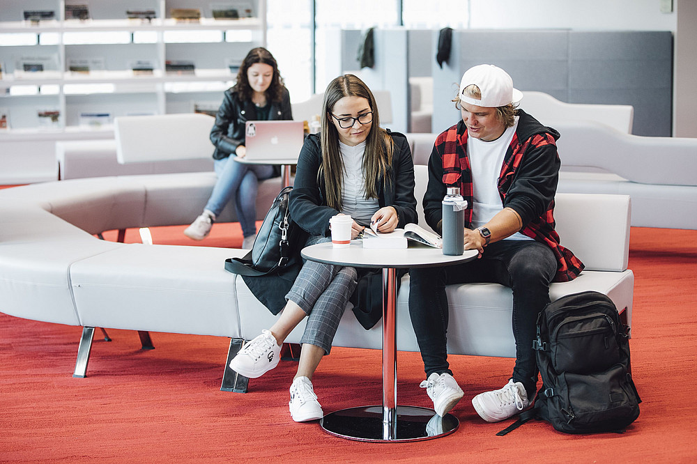 People sit in the library and read a document together ©Uni Graz/Kanizaj