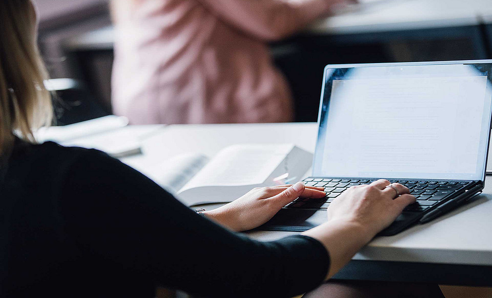 Studierende:r mit Händen auf einem Laptop