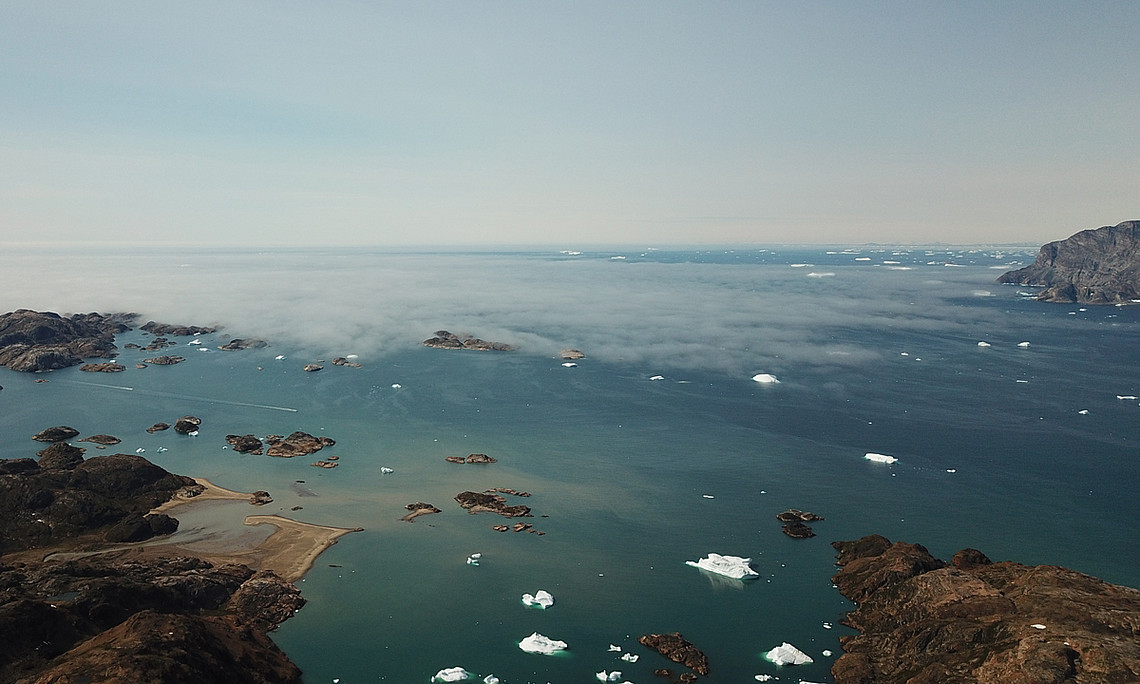 Der Ammassalikfjord, Ostgrönland. Die Schichtbewölkung in tiefen Lagen deutet auf eine Inversionsschicht hin, die den Luftaustausch mit höheren Schichten reduziert. Foto: Uni Graz/Abermann