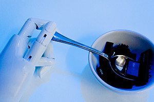 Roboterhand mit Löffel vor Suppenschüssel mit Tastatur-Einzelteilen
