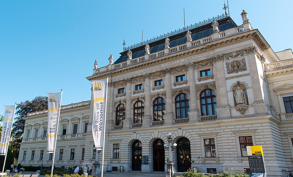Hauptgebäude der Uni Graz, davor Fahnen mit der Aufschrift "We work for tomorrow"
