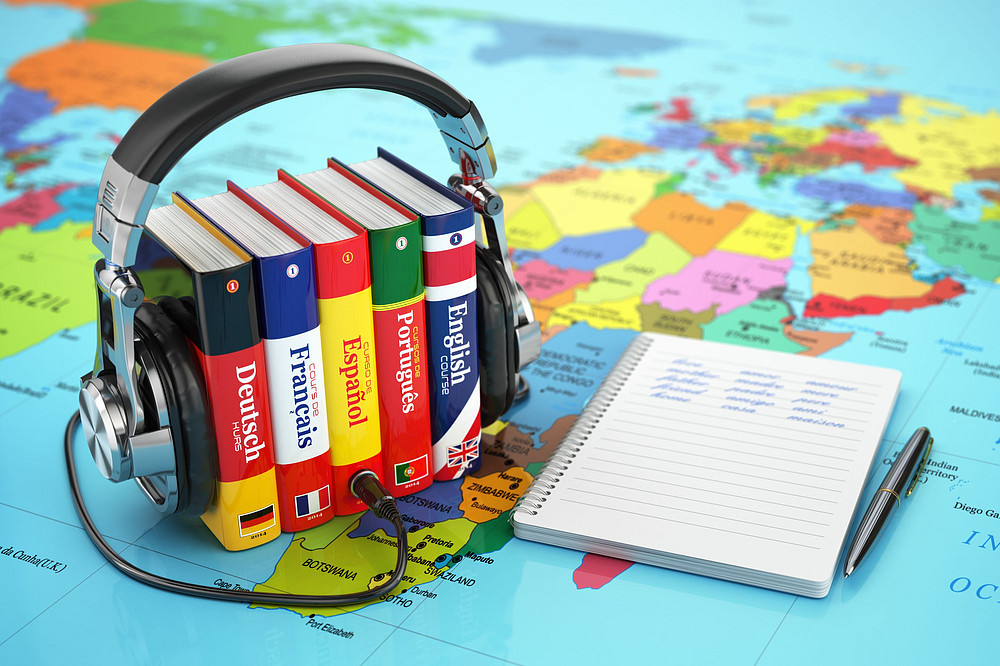 Das Bild zeigt einen Kopfhörer und Wörterbücher in verschiedenen Sprachen ©Maksym Yemelyanov - stock.adobe.com