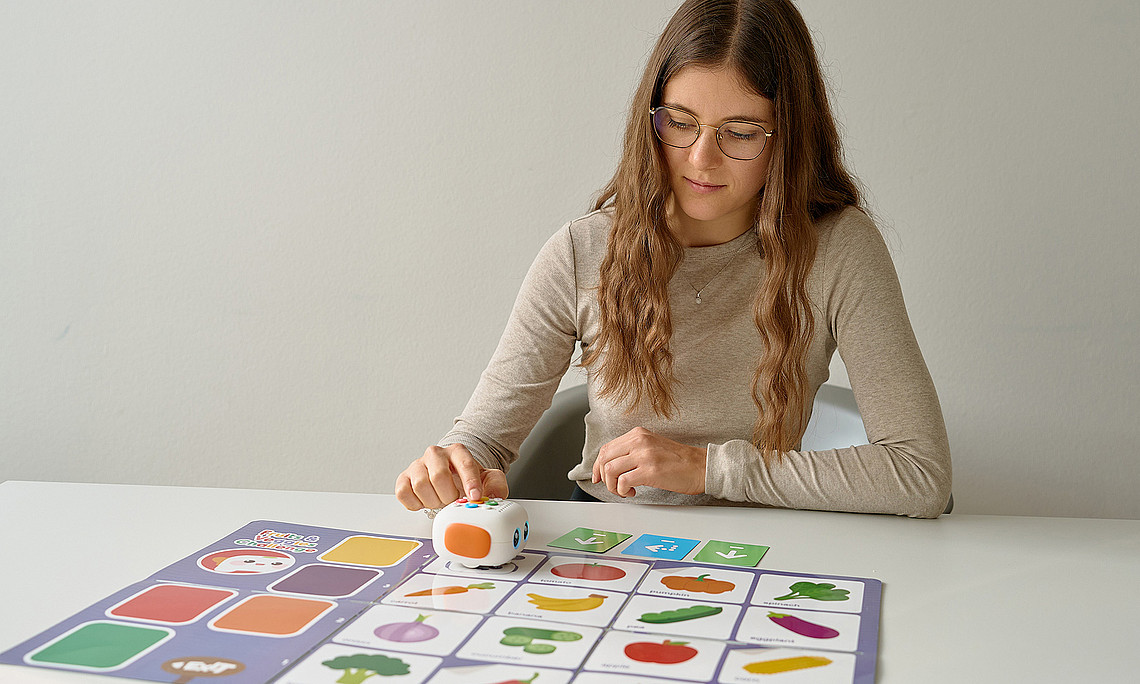 Belinda Jäger steuert einen kleinen Roboter auf einem Spielfeld