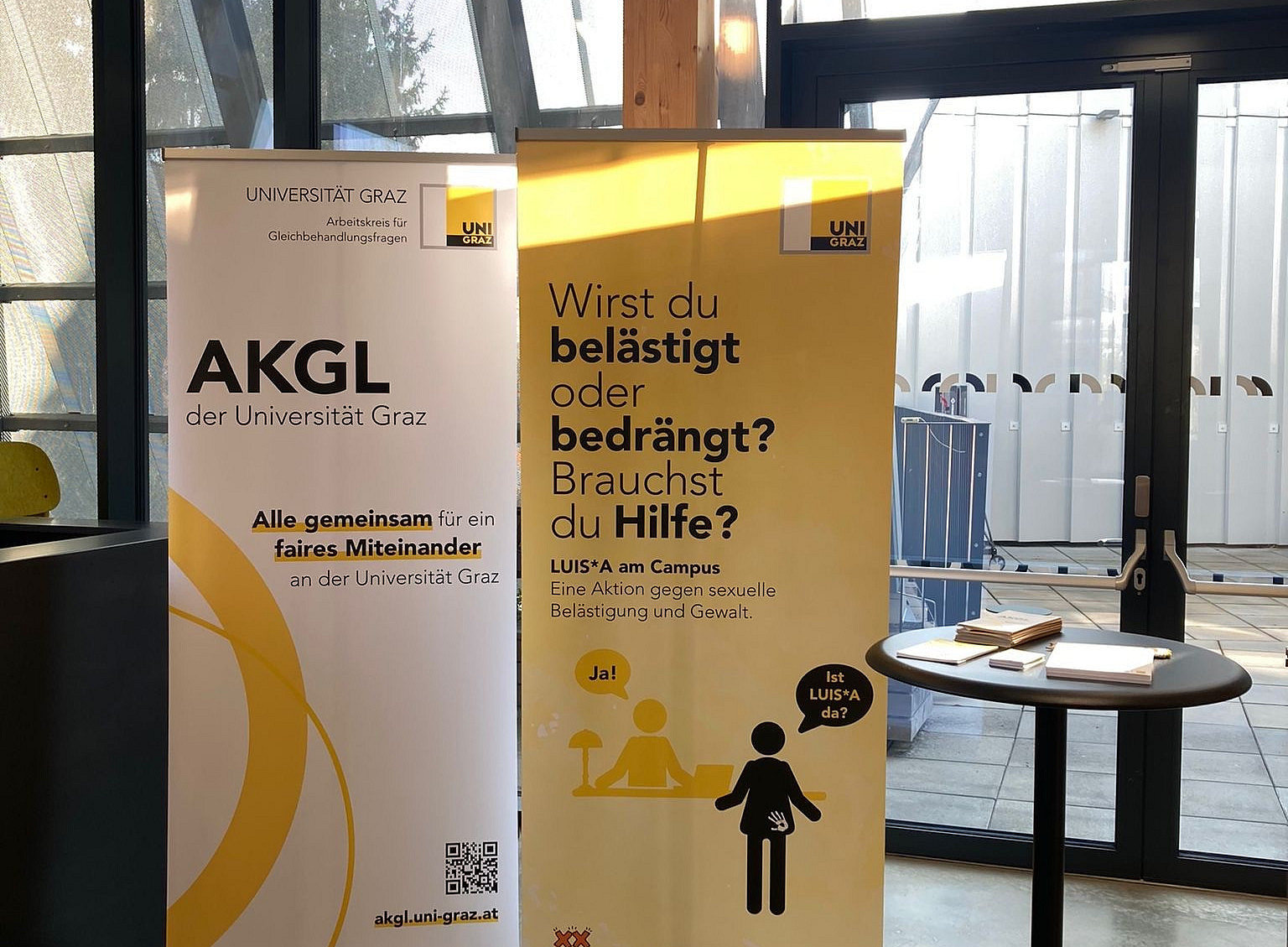 Ein Rollup von LUISA und vom AKGL stehen neben einem schwarzen Stehtisch ©AKGL-Büro Uni Graz