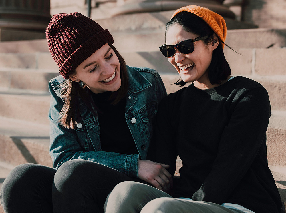 2 Junge Frauen sitzen auf Treppenstufen und lachen ©Anna Selle by unsplash.com