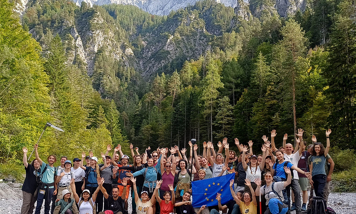 Group of students – around 50 people – in a valley, with a mountain backdrop, in the Gesäuse National Park