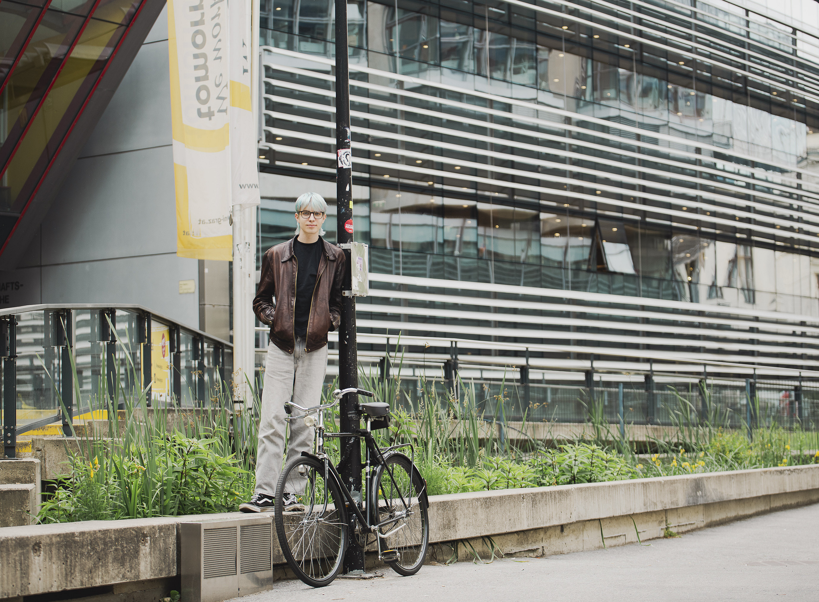 Ein junger Mann steht auf einer Stufe, dahinter ein Gebäude ©Uni Graz/Tzivanopoulos