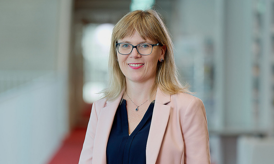 Portrait of theologian Martina Bär standing in the corridor of the university library