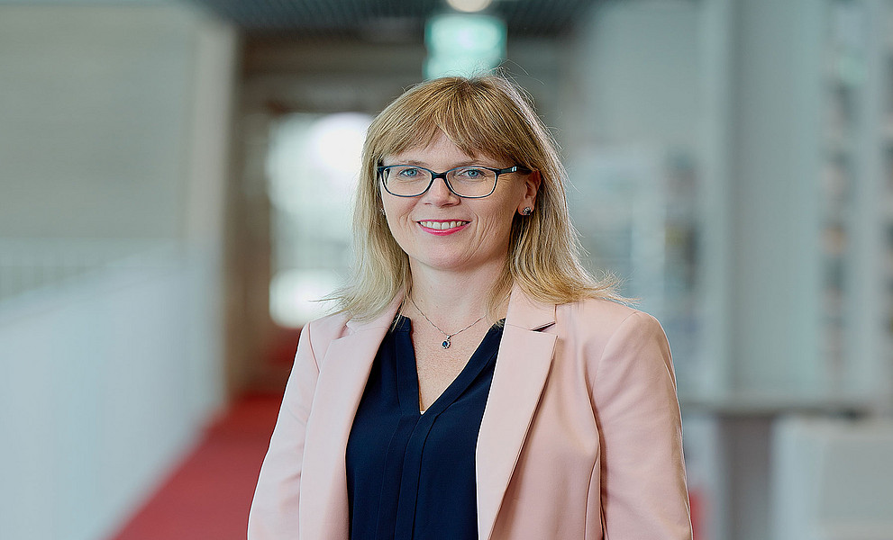 Porträt der Theologin Martina Bär stehend im Gang der Universitätsbibliothek