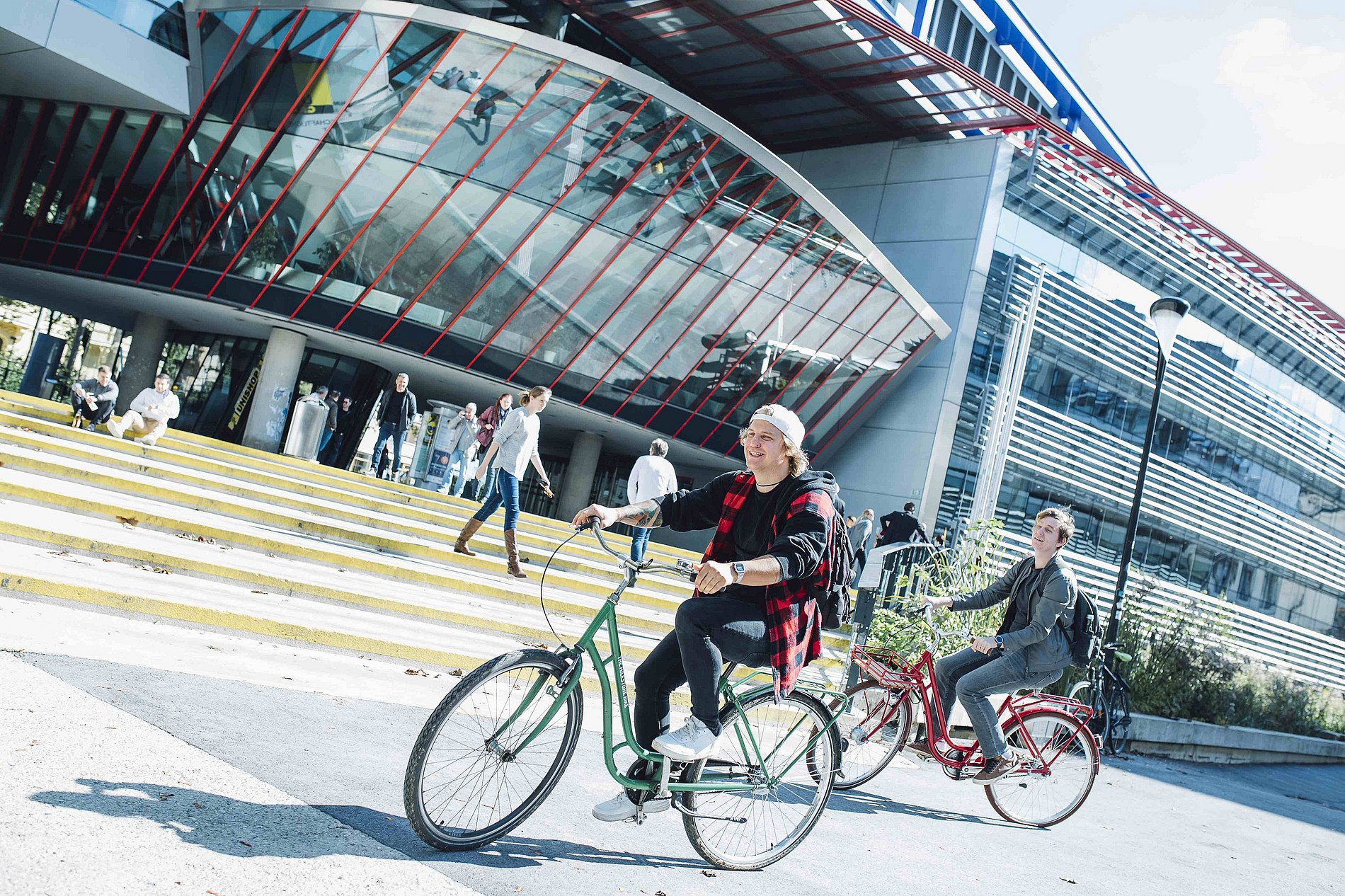 Two young men on bicycles in front of the RESOWI building, subject image Study Department at the University of Graz ©Uni Graz/Kanizaj