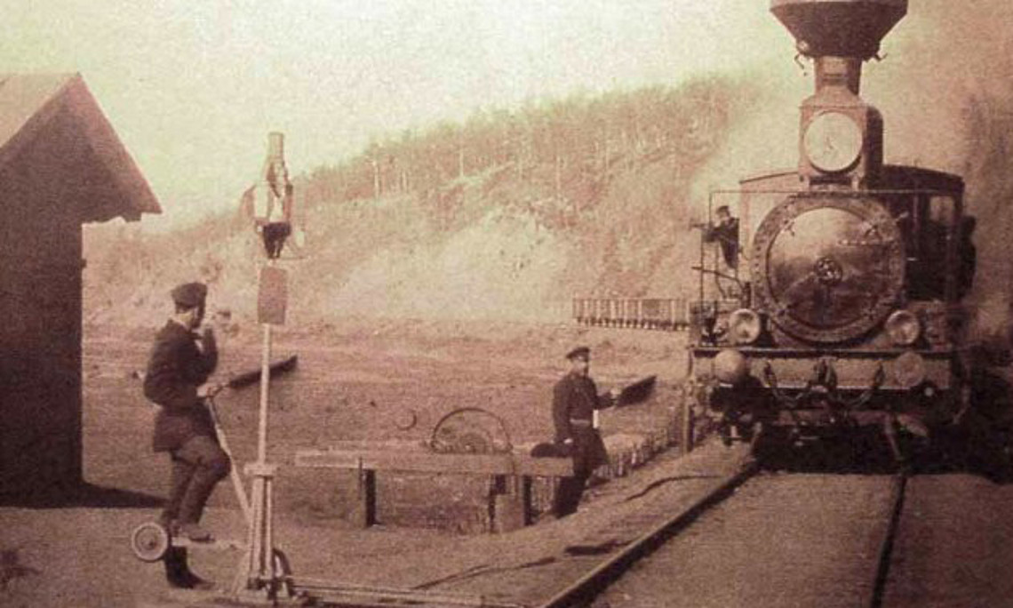 Seit der Zeit der Zaren fungierten Züge als imperiale Werkzeuge - auch in der späteren Sowjetunion. Das Trillern einer Pfeife oder die schnaufende Lokomotive suggerieren deshalb in der Belletristik oft latente Bedrohung, wie auch in Tschingis Aitmatows Roman „Ein Tag länger als ein Leben“. Hier eine Szene aus dem Jahr 1903 am Bahnhof von Chilok (Transbaikalien). Foto: https://commons.wikimedia.org/ CC by 4.0. 