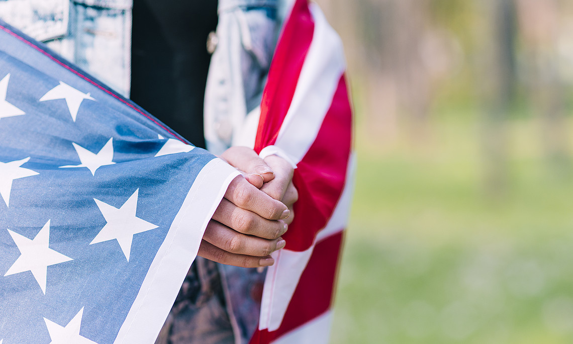 nonymous female wrapping in american flag while praying