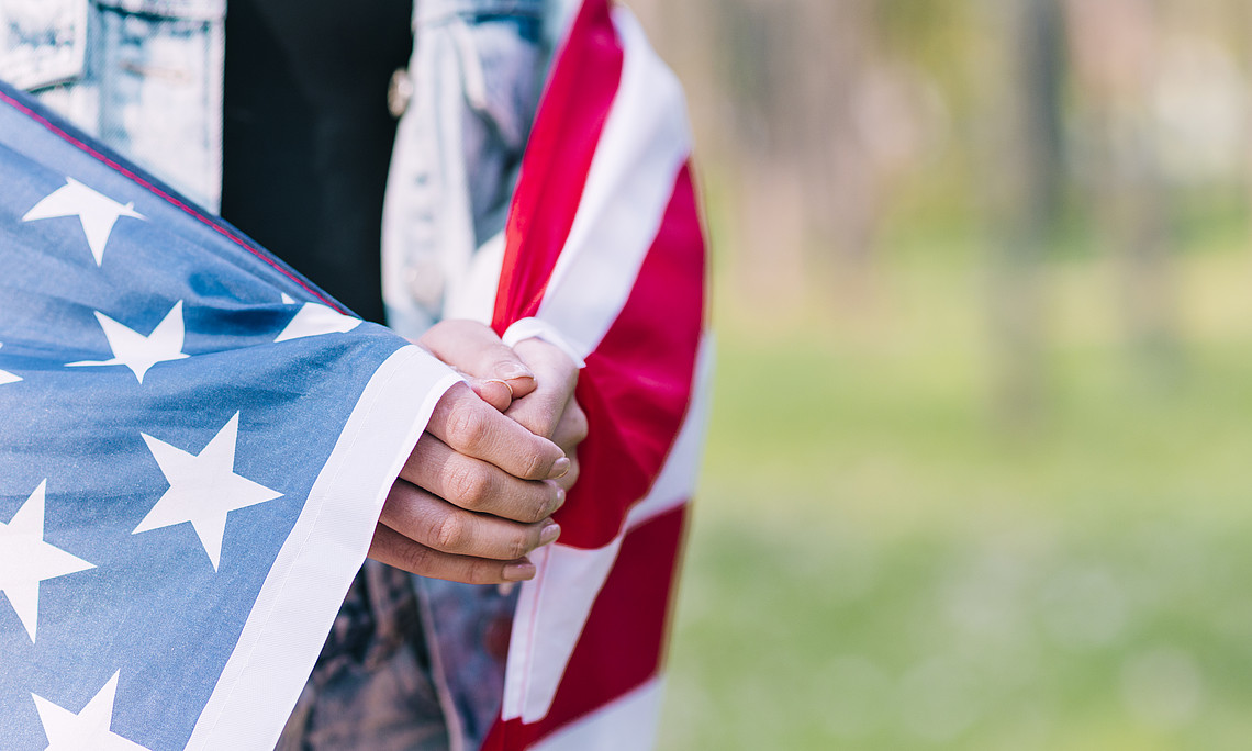 Gefaltete Hände unter amerikanischer Flagge