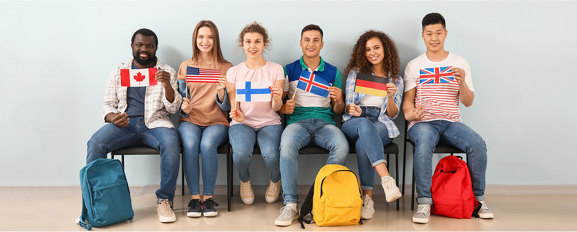Sprachkurse: Menschen sitzen neben einander mit unterschiedlichen Flaggen (Foto: Adobe Stock) 