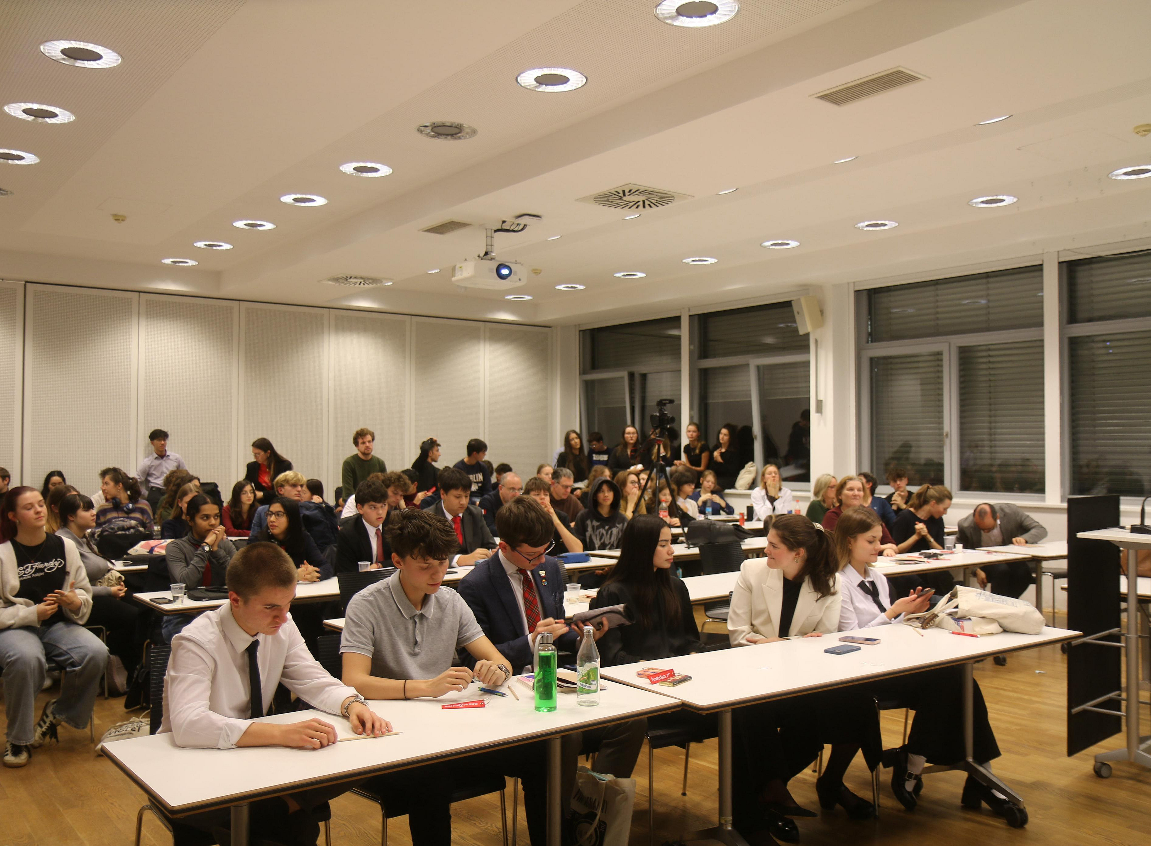 Jugendliche im Großen Hörsaal des UZT, im Vordergrund sitzen die 2 Finalisten-Teams nebeneinander und warten auf den Ausgang bzw. die Bewertung des Finales 