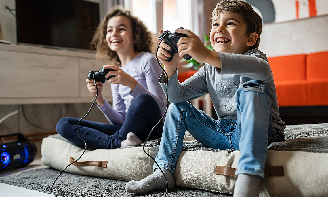 boy and girl playing video game console using controller while sitting at home