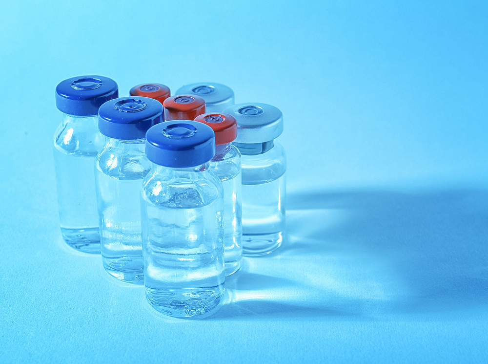 Acht Impfstoff-Behälter vor einem blauen Hintergrund ©africa-studio.com (Olga Yastremska and Leonid Yastremskiy)