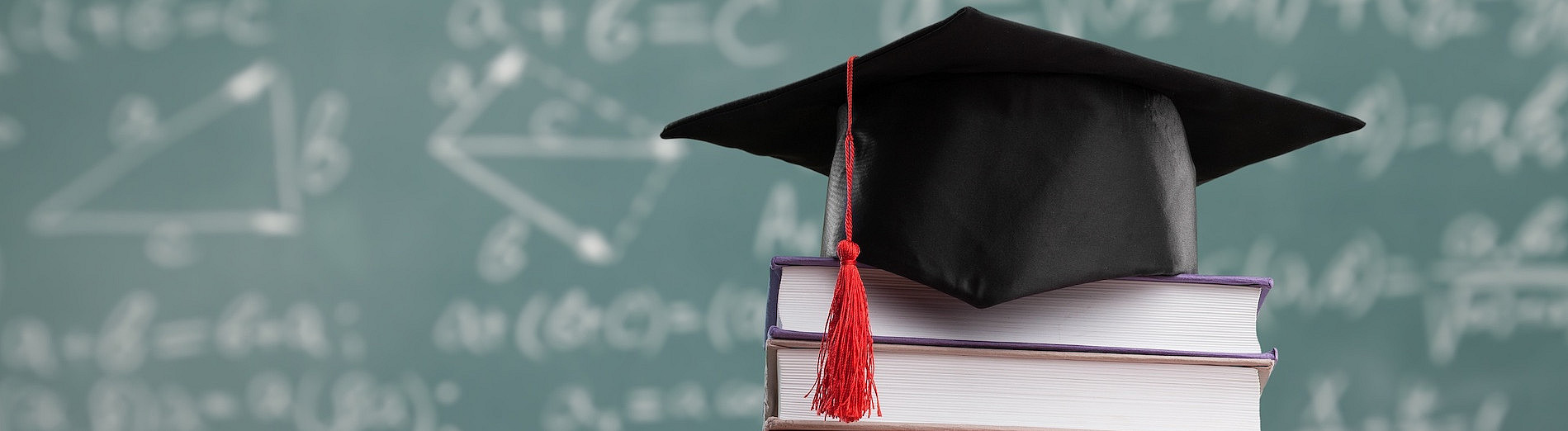 graduaten hat on books with blackboard in background ©BillionPhotos.com - stock.adobe