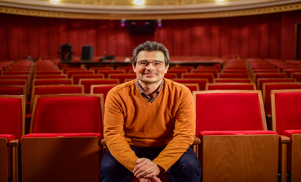 Ein Mann sitzt auf den roten Sesseln im Saal des Grazer Schauspielhauses