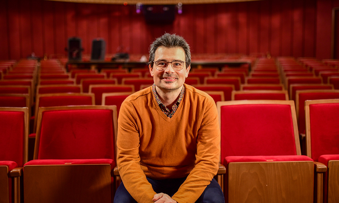 Ein Mann sitzt auf den roten Sesseln im Saal des Grazer Schauspielhauses