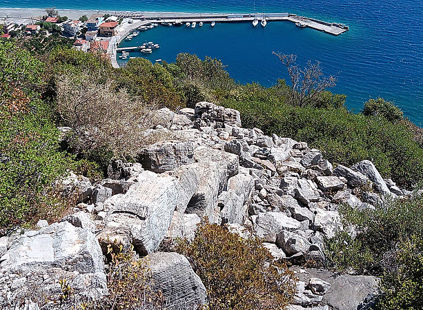 Blick auf die antiken Überreste mit dem modernen Hafen Plöaka im Hintergrund. 