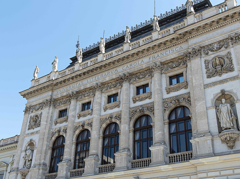 Das Hauptgebäude der Uni Graz in Frontansicht an einem strahlend, hellen Tag, und Photopoint der Uni Graz ©Uni Graz/Julina Raggautz