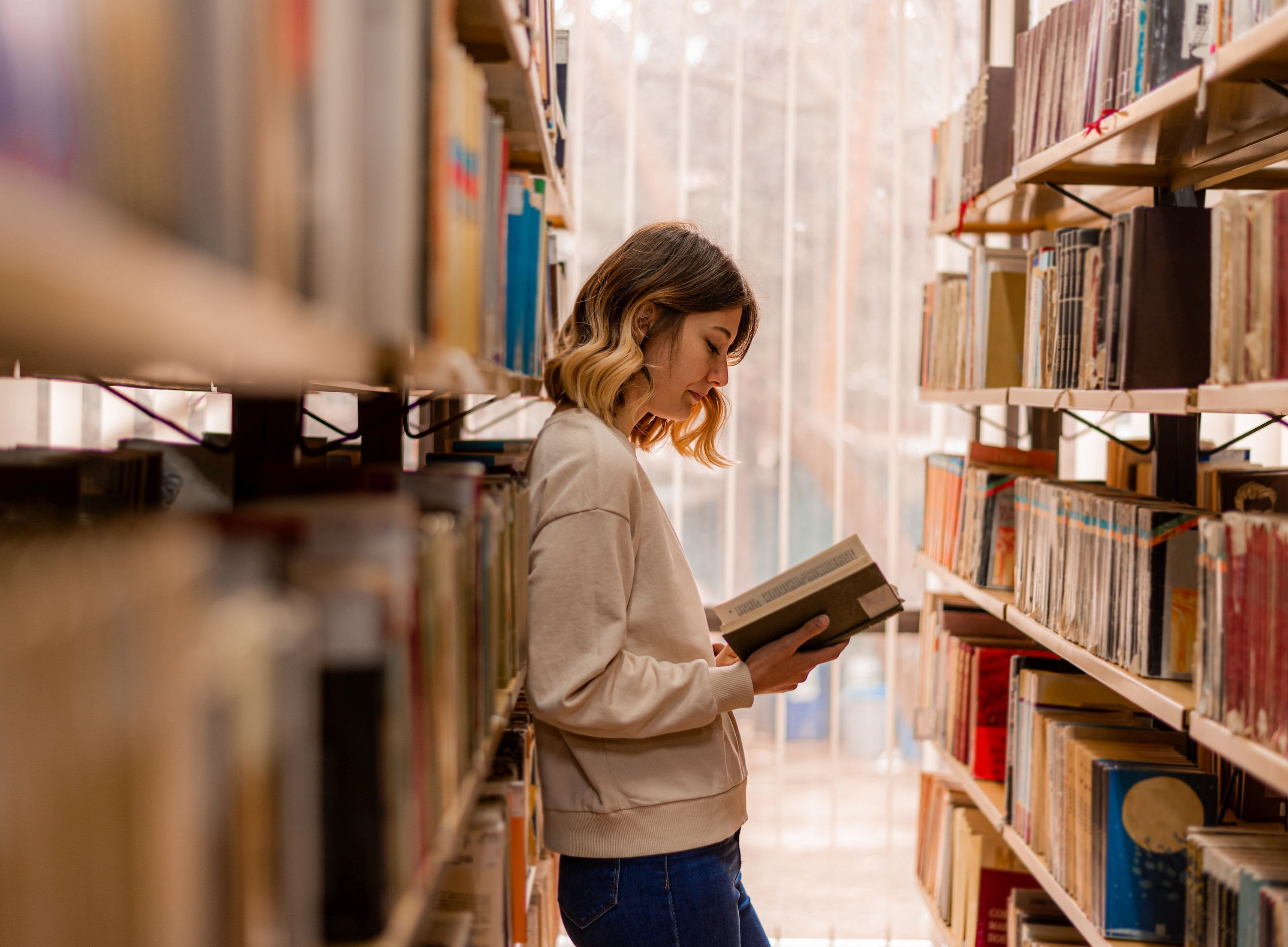 Stock photo of person reading a book in a library ©qunica.com - stock.adobe.com