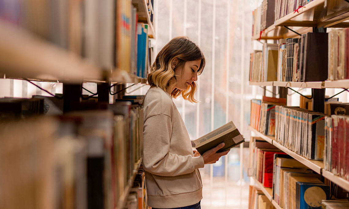 Stock photo of person reading a book in a library