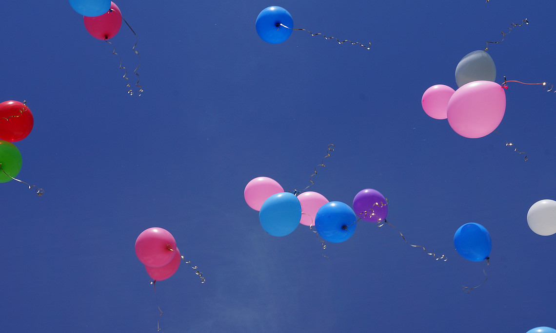 Bunte Luftballons fliegen in Richtung Himmel.