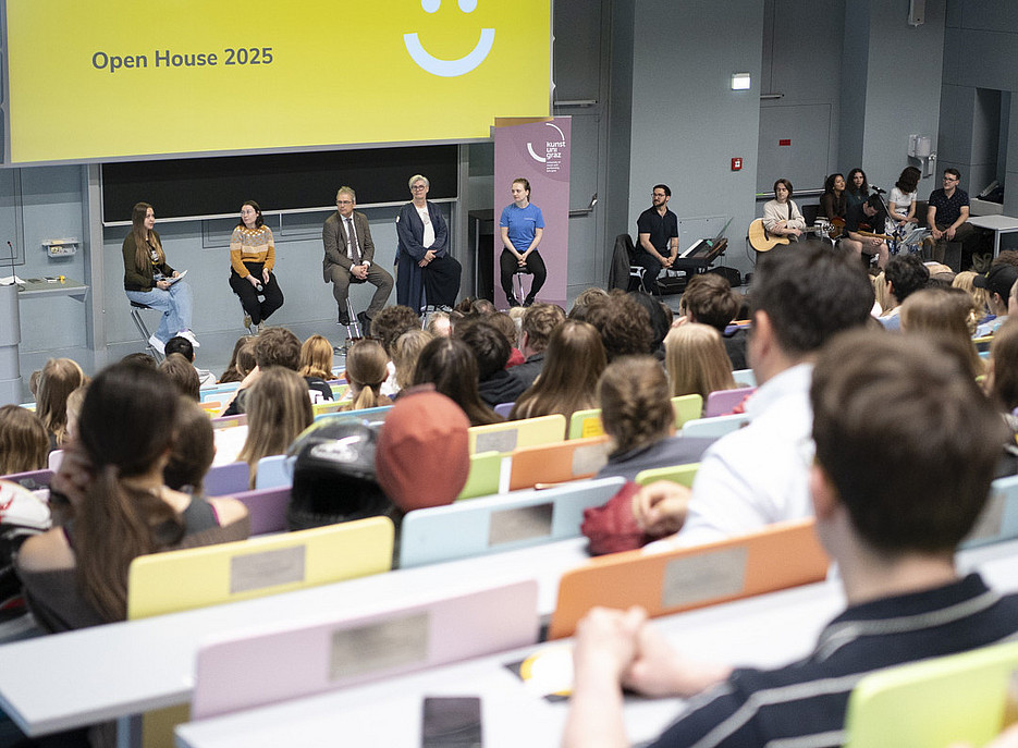 Viele junge Erwachsene sitzen in einem großen Hörsaal. Auf eine Leinwand ist der Satz "Schön, dass du da bist!" projiziert. ©Uni Graz/Angele