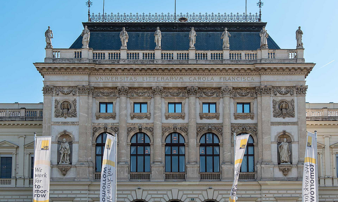 Hauptgebäude der Uni Graz mit vier "We work for tomorrow"-Fahnen davor