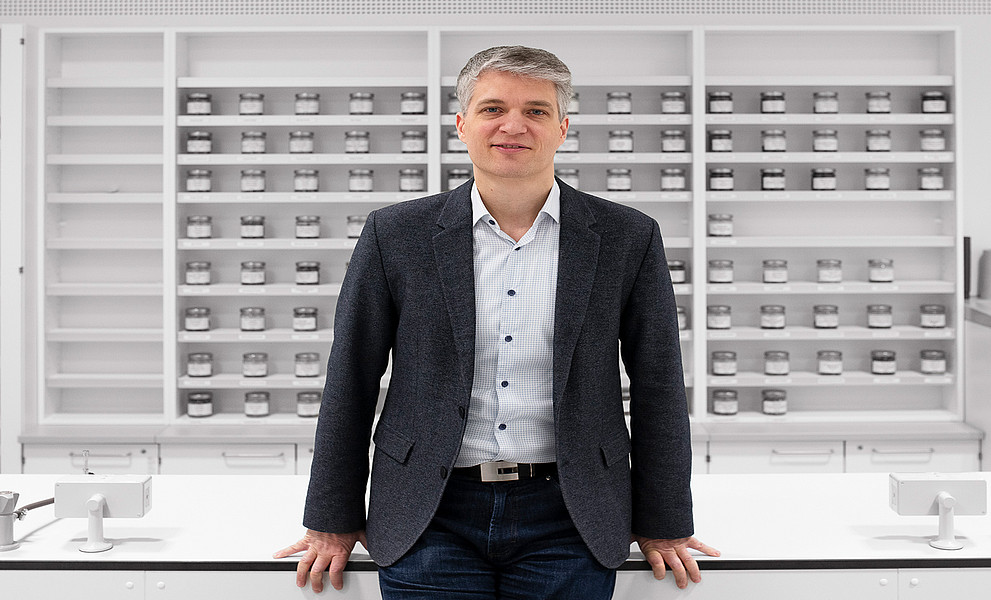 Andreas Koeberle vor einer Regalwand mit verschraubbaren Gläsern