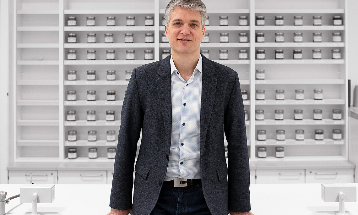 Andreas Koeberle in front of a wall of shelves with screw-in glasses