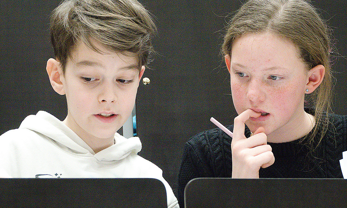 Two children taking part in a mathematics competition in a lecture hall at the University of Graz