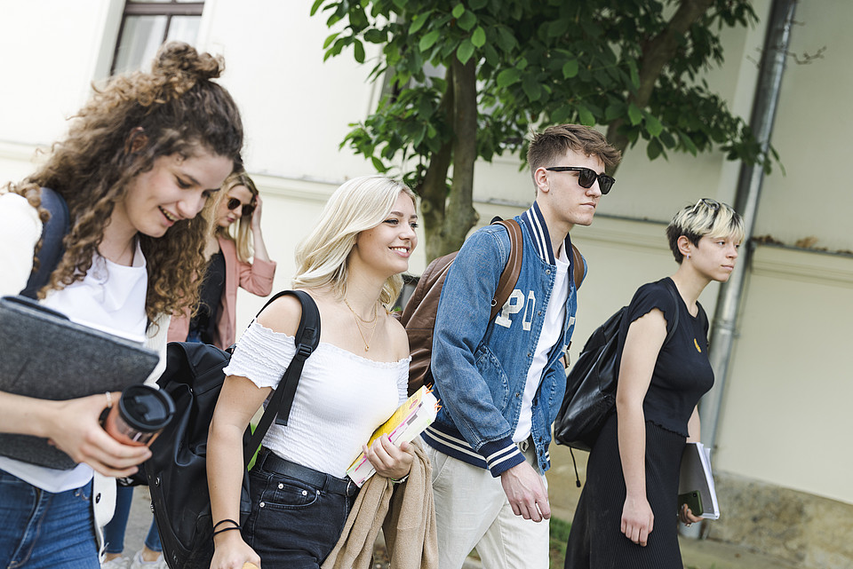 Studierende gehen nebeneinander im Freien