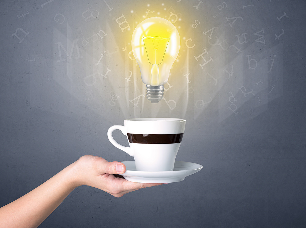 Female hand holding coffee cup Teetasse mit einer Glühbirne