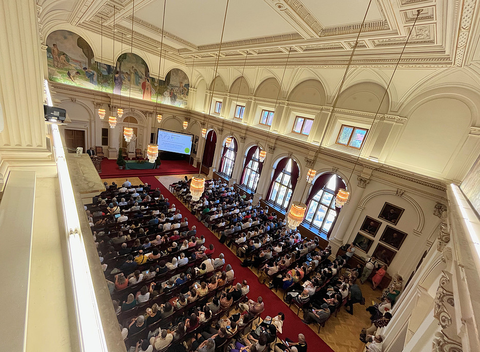 Viele Leute sitzen in einem großen Saal 