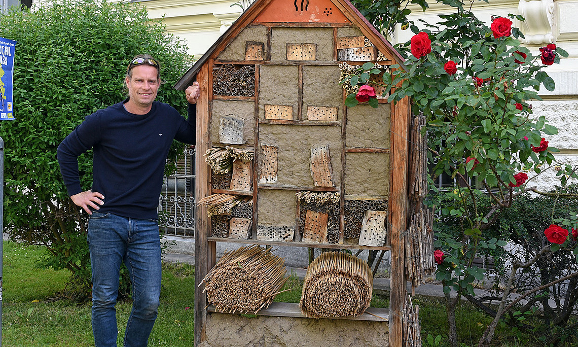 Biologist Gernot Kunz next to the insect hotel he designed on the campus of the University of Graz