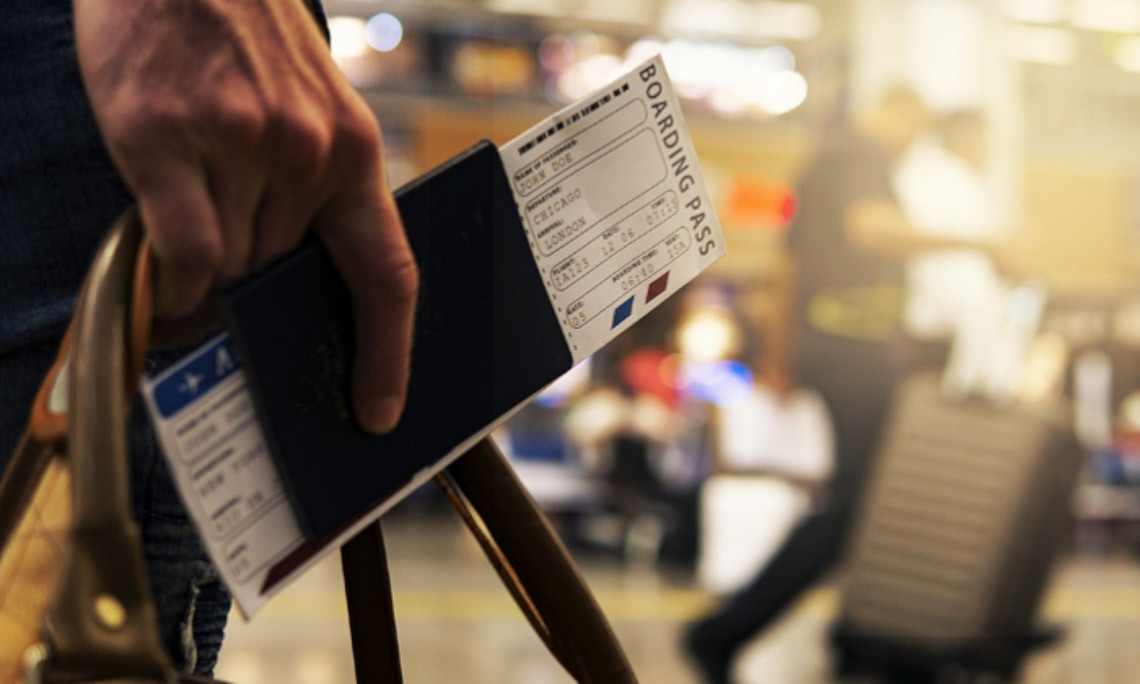 Hand trägt Reisepass und Reisetasche