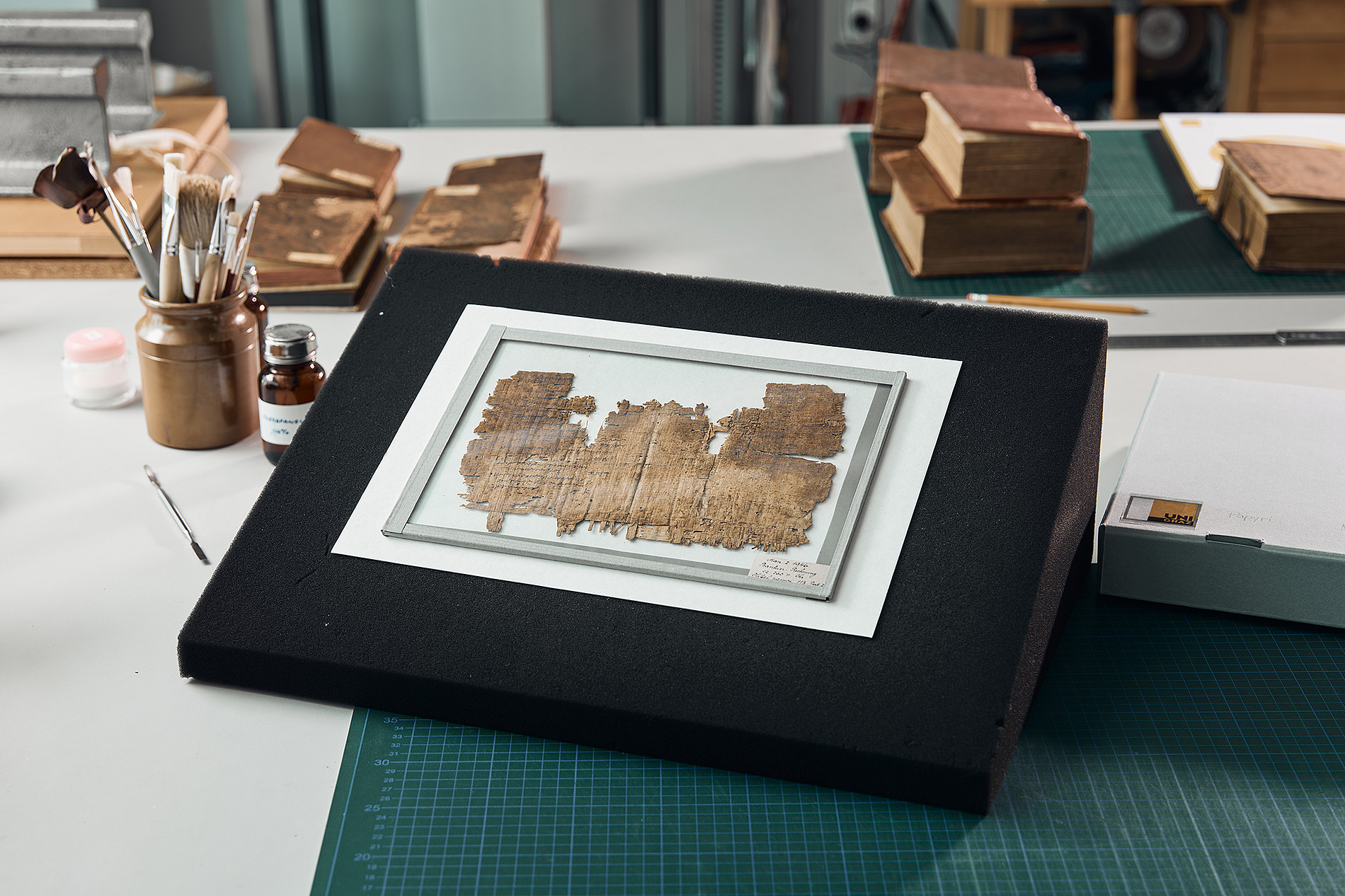 Papyrus-Fragment hinter Glas in der Restaurierungswerkstätte der Universität Graz ©    Uni Graz/Kernasenko