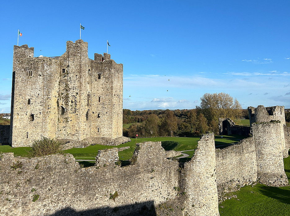 eine irische Burgruine mit eingestürzten Mauern auf grüner Wiese vor einem blauen Himmel ©Uni Graz/Annika Freidorfer