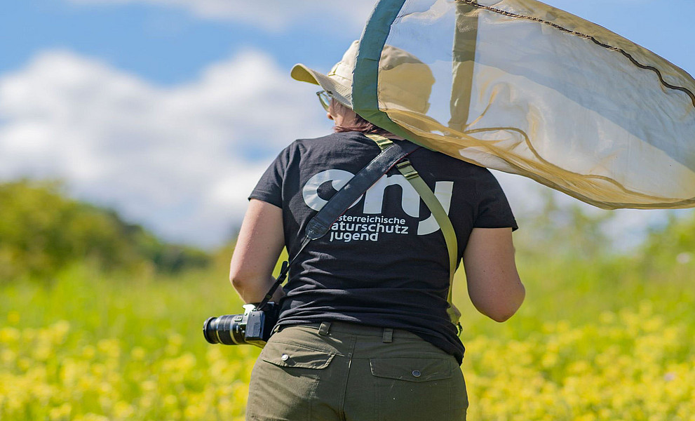 Studierende der Uni Graz mit Fotoapparat und Schmetterlingsnetz in der Natur