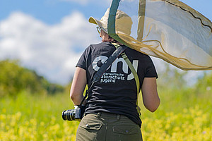 Studierende der Uni Graz mit Fotoapparat und Schmetterlingsnetz in der Natur