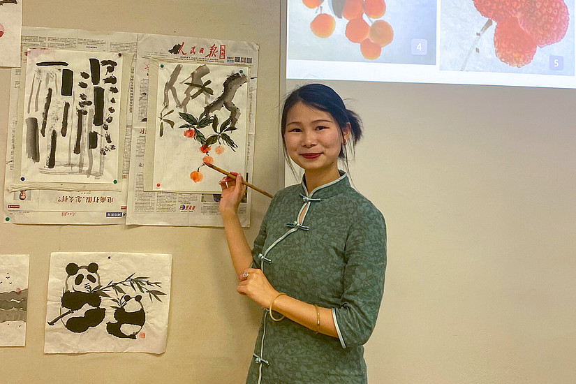 Kursleiterin des Malkurs zeigt an der Tafel die Maltechniken der chinesischen Malerei vor