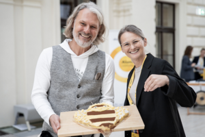 Helmut Jungwirth mit einer Mitarbeiterin der Uni Graz, er hält eine bienenförmige Torte in der Hand