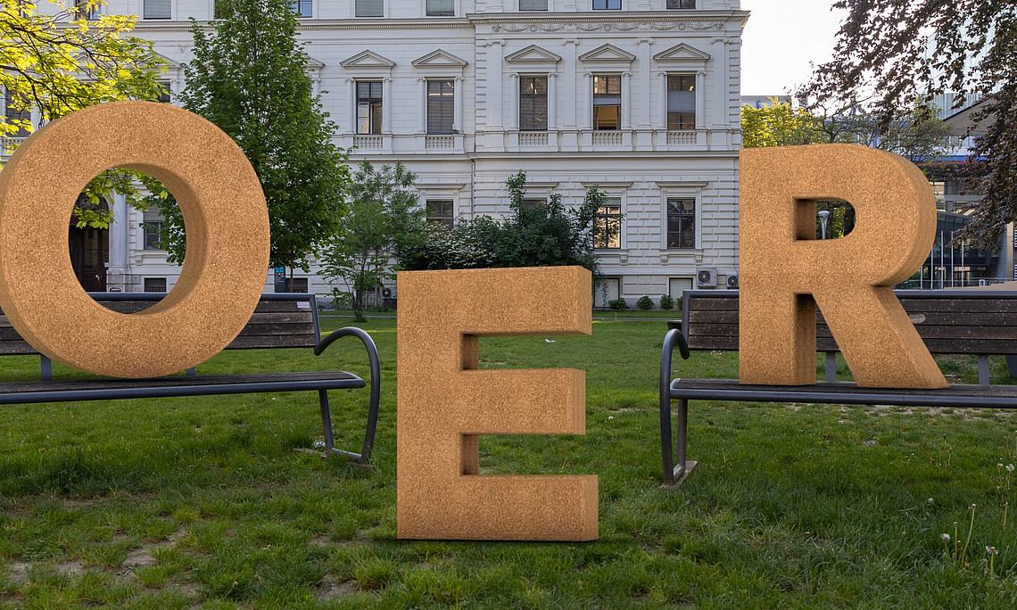 OER-Buchstaben auf Wiese vor Uni-Gebäude