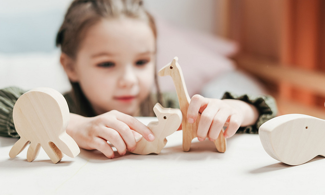 Kinder lernen über Tiere, Mädchen spielt mit Holztieren