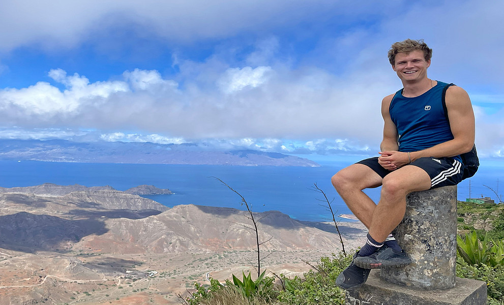 Leo Thosold sitzt auf einem Felsen, im Hintergrund das Meer