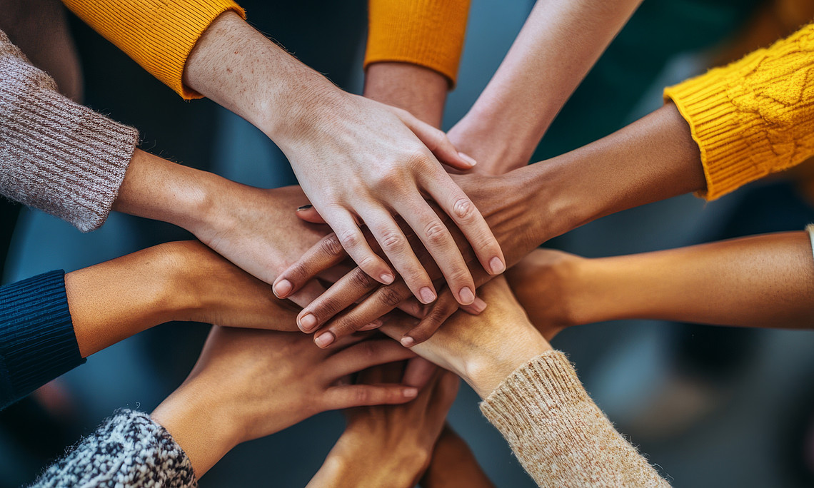 People who work together and put their hands on them to emphasise the collaboration in the forum